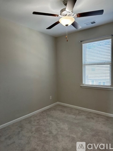 A room with a ceiling fan and a window with blinds.