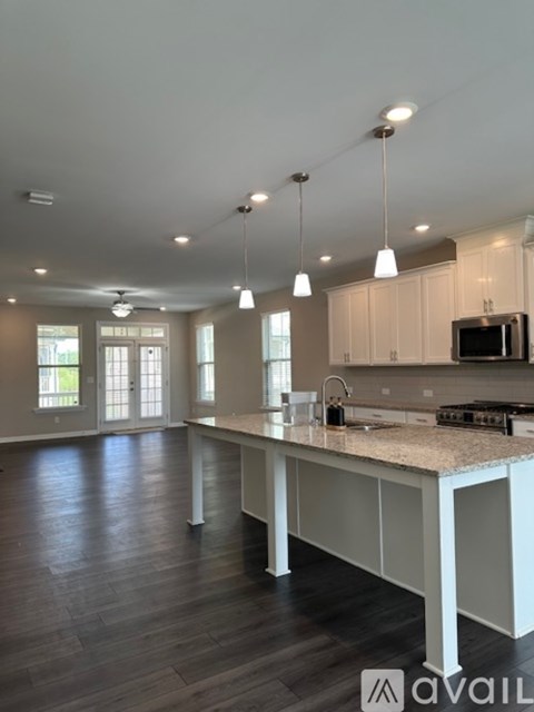 A kitchen with a large island and pendant lights.