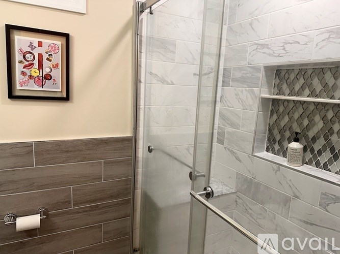A bathroom with a tiled shower and a framed picture on the wall.