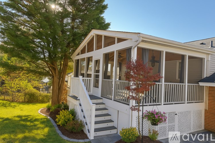 A house with a white porch and a tree with red leaves.
