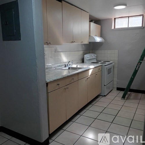 A kitchen with white tiles and beige cabinets.