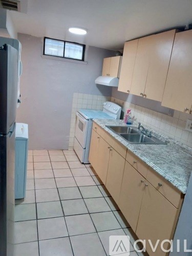 A kitchen with a refrigerator, sink, and cabinets.