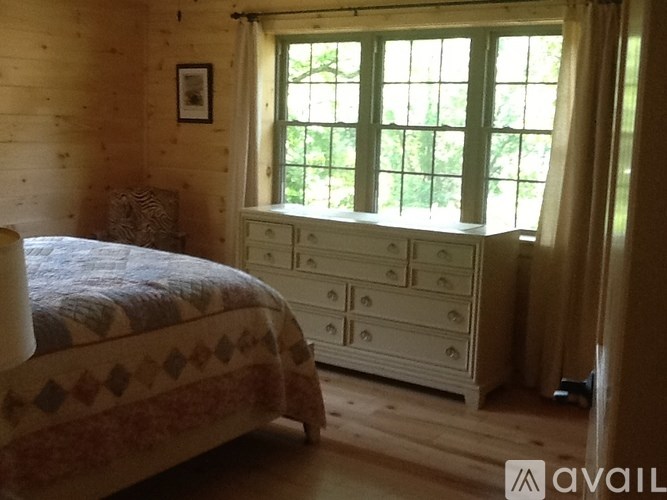 A bedroom with a bed, dresser, and window.