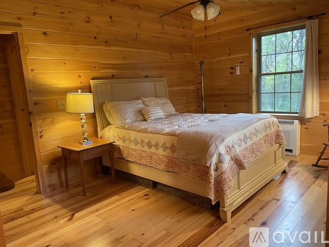 A bedroom with a bed, nightstand, and lamp.