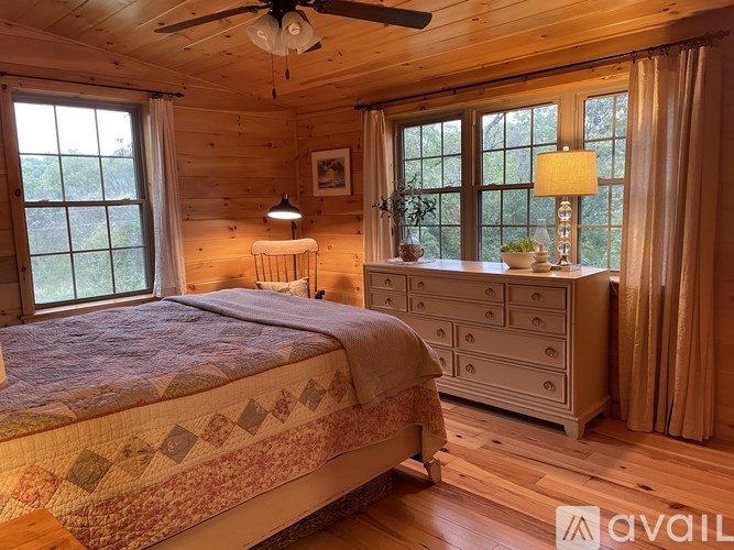 A bedroom with a bed, dresser, and window.