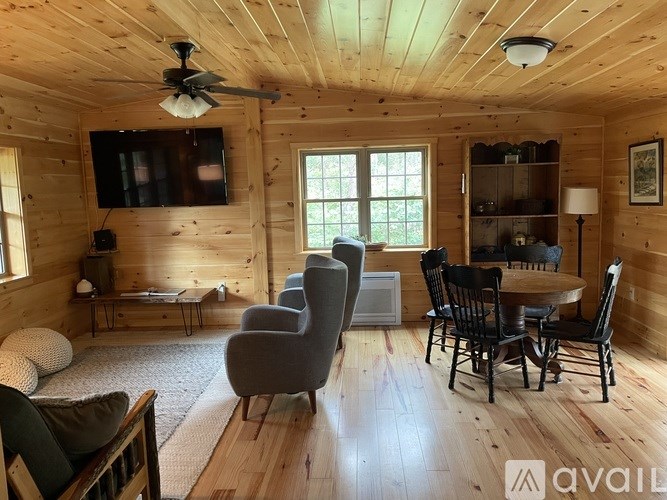 A living room with a wooden ceiling and a television mounted on the wall.