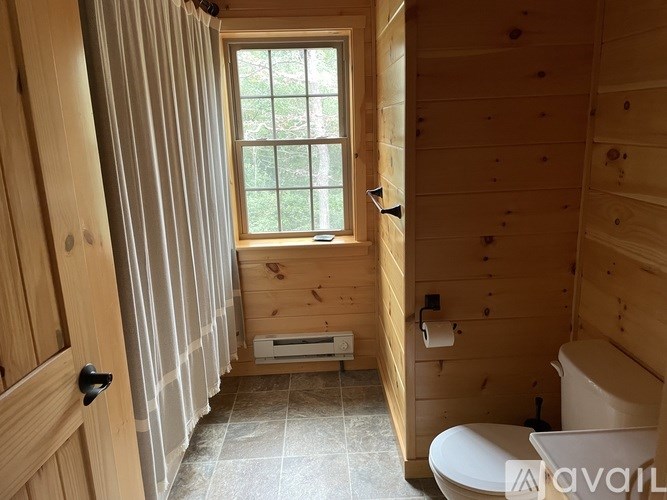 A bathroom with a window and a toilet.