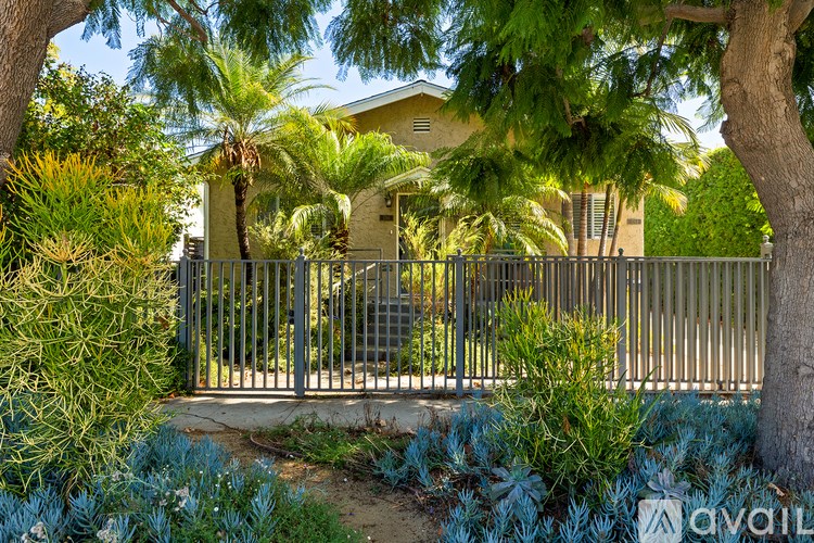 A house is seen through a gate surrounded by greenery.