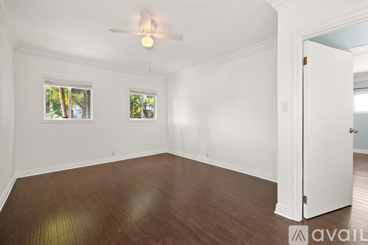 A room with a ceiling fan and two windows.