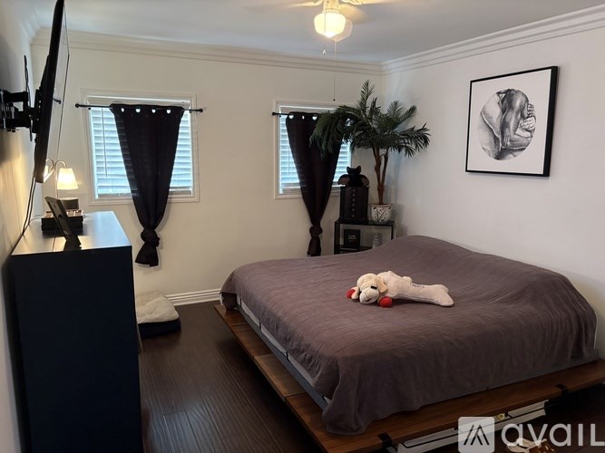 A bedroom with a bed, a plant, and a painting on the wall.