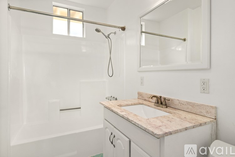 A bathroom with a marble countertop and a glass shower enclosure.