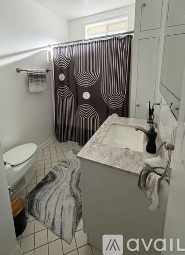 A bathroom with a toilet, sink, and shower curtain.