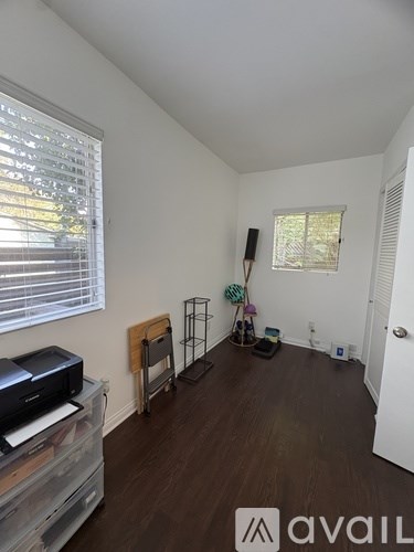 A room with a printer on a desk and a chair with a blanket draped over it.