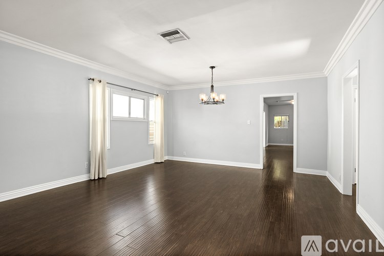 A spacious room with wooden floors and a chandelier.