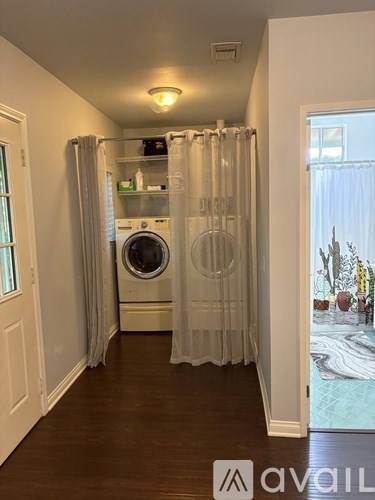 A laundry room with a washer and dryer, a curtain, and a window.