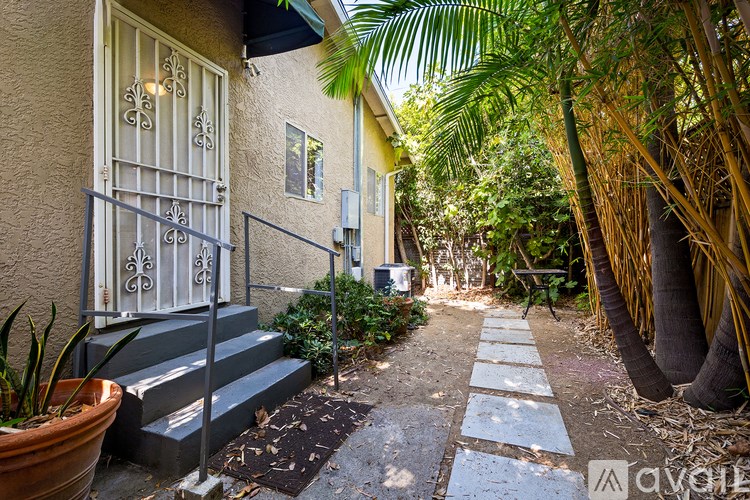 A narrow alley with a house on the left and a tree on the right.