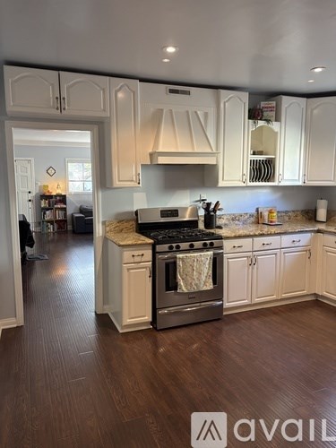 A kitchen with white cabinets and a wooden floor.