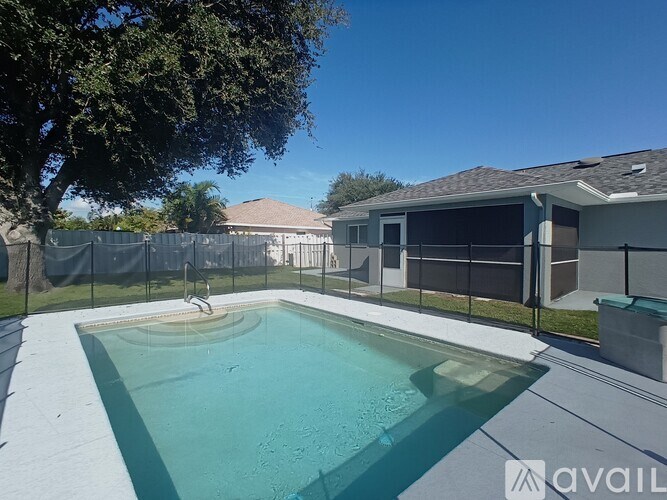 A pool surrounded by a fence and a house in the background.