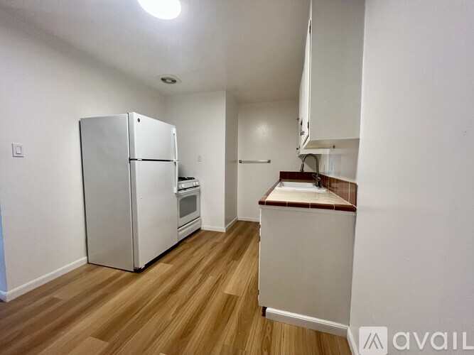 A kitchen with a refrigerator, oven, and sink.