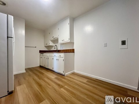 A kitchen with white cabinets and a refrigerator.