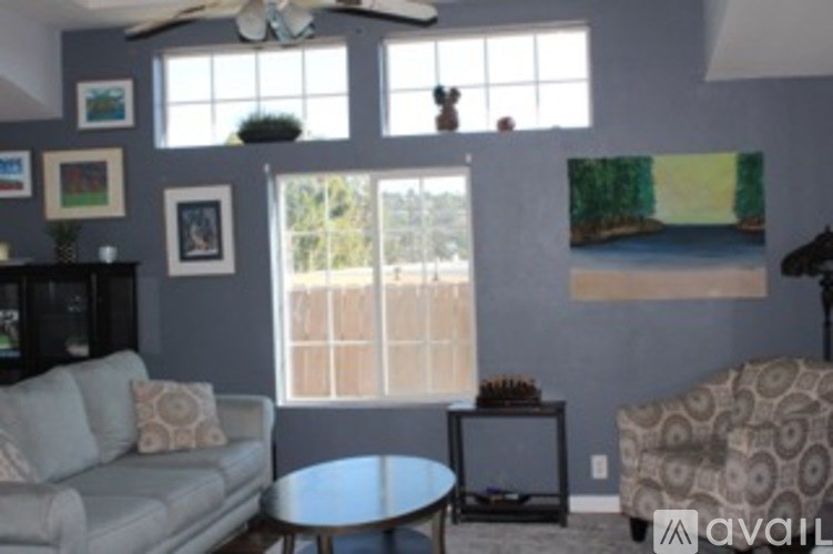 A living room with a grey couch and a ceiling fan.