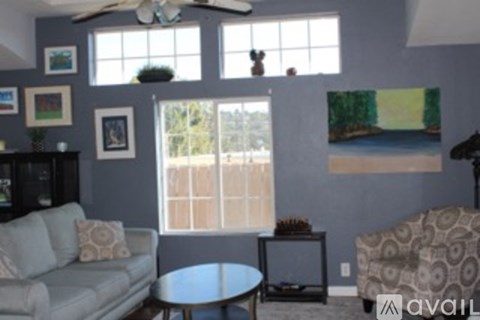 A living room with a grey couch and a ceiling fan.