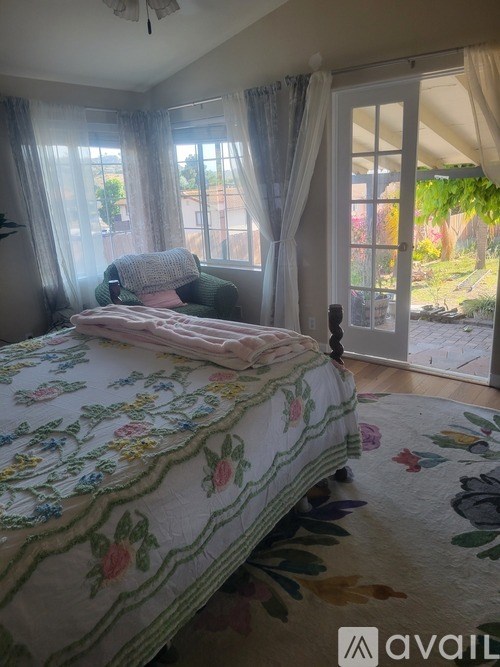 A bedroom with a floral bedspread and a window with curtains.