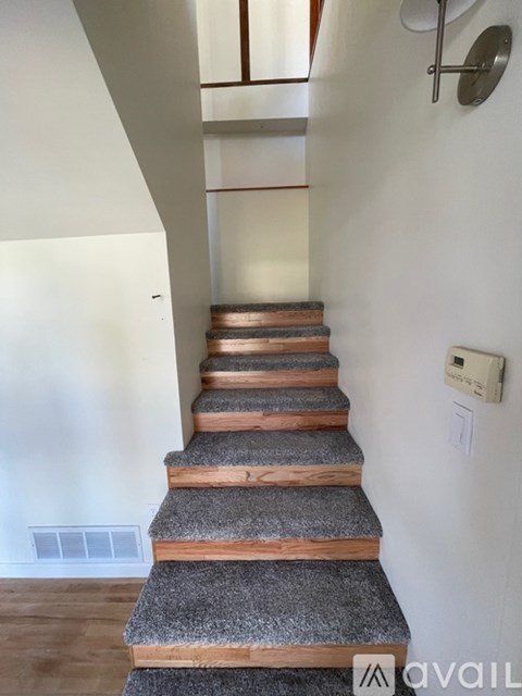 A staircase with wooden steps and a grey carpeted runner.