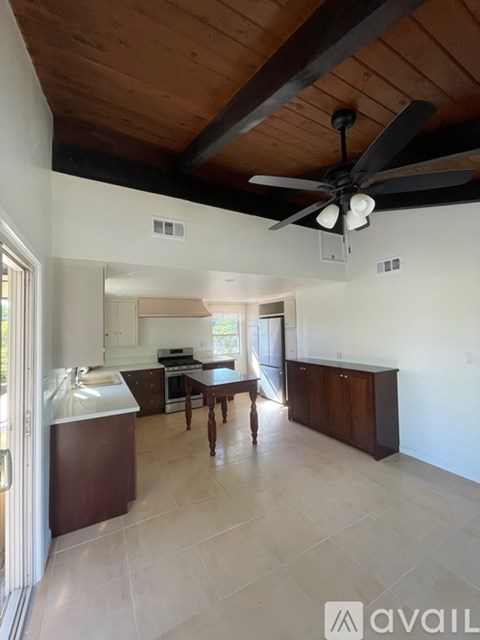 A kitchen with a ceiling fan and a dining table.