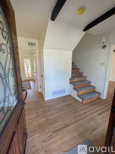 A hallway with wooden floors and a staircase.