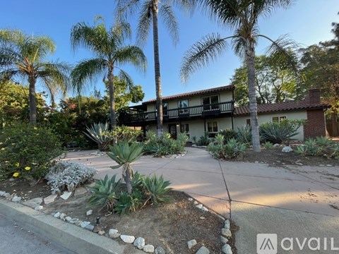 A house with a balcony and a palm tree in front.