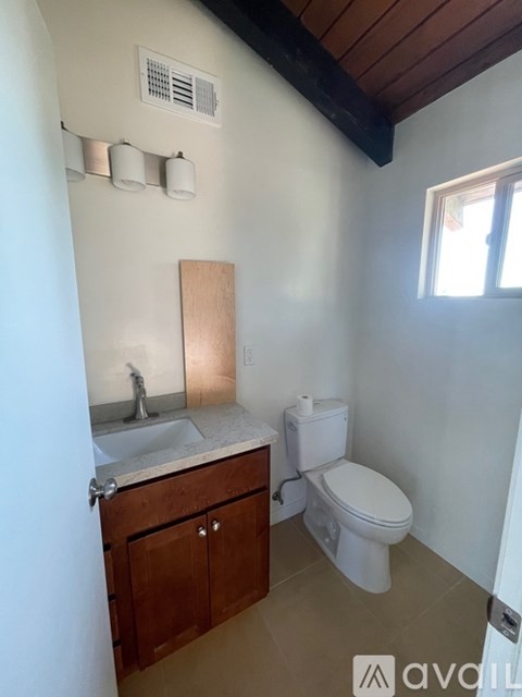 A bathroom with a toilet, sink, and wooden cabinet.