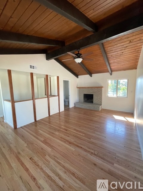 A room with wooden floors and a fireplace is available for rent.