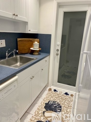 A kitchen with white cabinets and a blue backsplash.