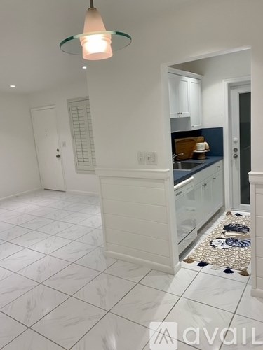 A kitchen with white cabinets and a white tiled floor.