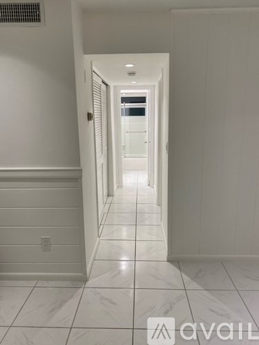 A long hallway with white walls and marble floors.