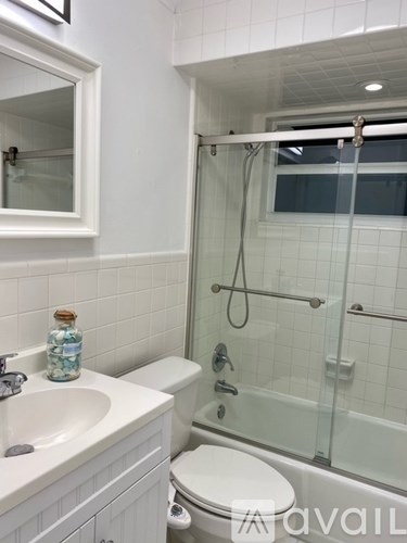 A white bathroom with a glass shower stall and a toilet.