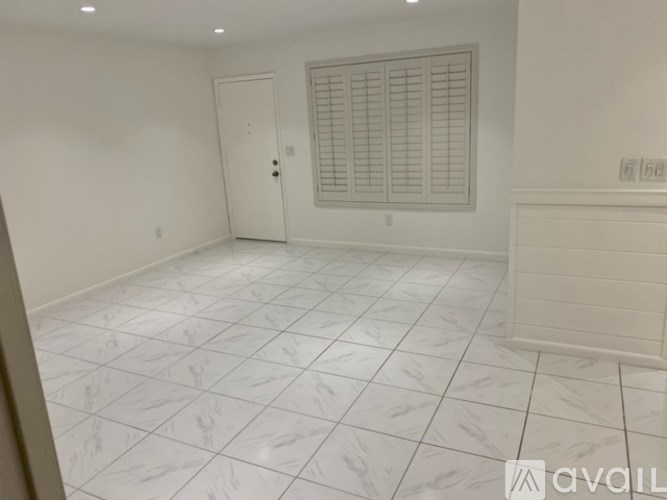 A room with white tiled flooring and a window with blinds.