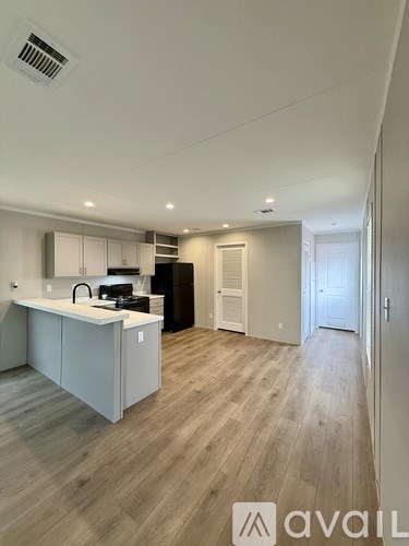 A modern kitchen with wooden flooring and white cabinetry.
