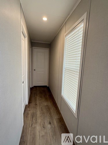 A hallway with wooden floors and white walls.
