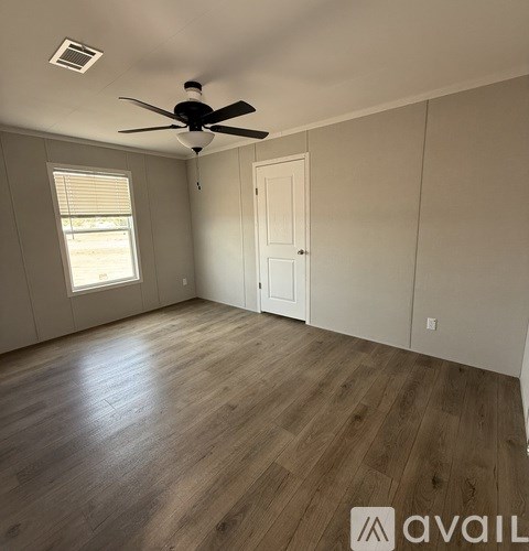 A room with a ceiling fan and wooden flooring.