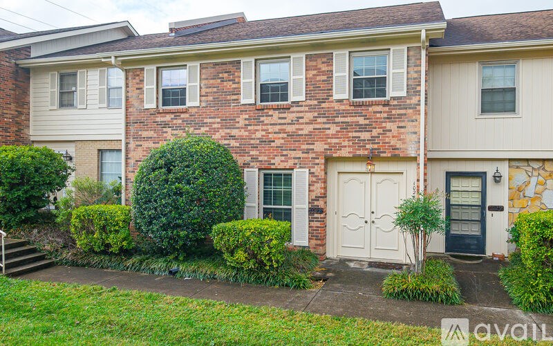 A brick house with a white door and a green bush in front.