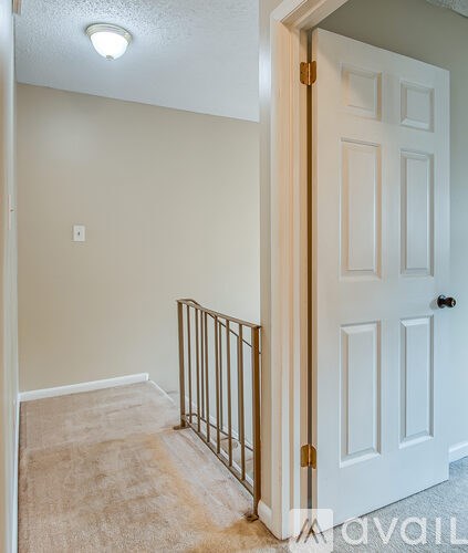 A white door with a gold handle is open to a hallway.