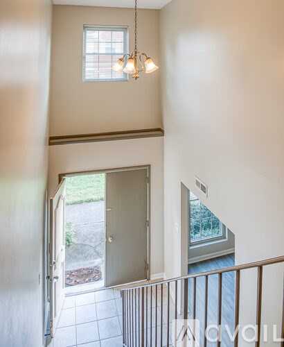 A chandelier hangs from the ceiling in a room with a doorway leading to a backyard.