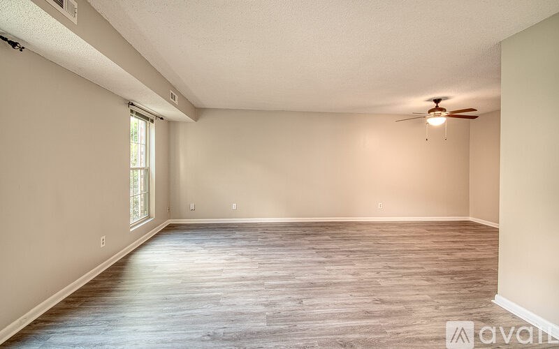 A spacious room with wooden flooring and a ceiling fan.