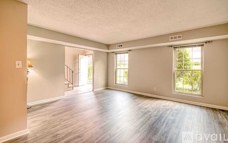 A spacious room with wooden flooring and a staircase leading to another level.
