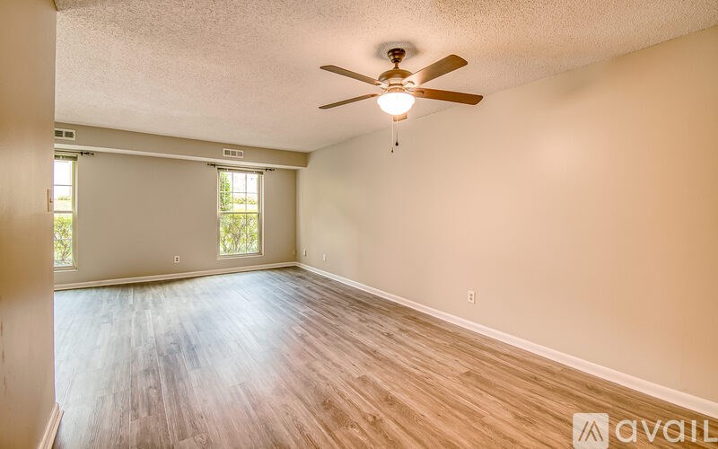 A room with a ceiling fan and wooden flooring.