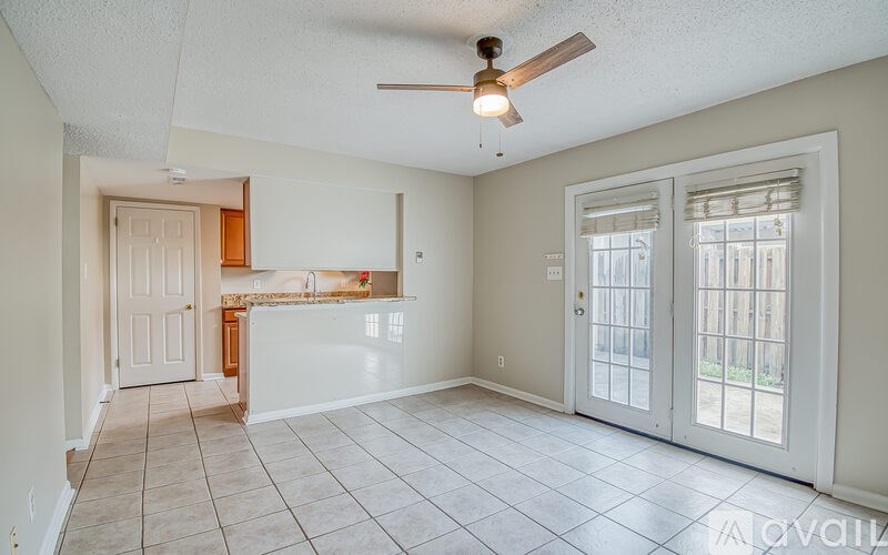 A spacious living room with a ceiling fan and tiled flooring.