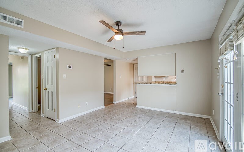 A spacious room with a ceiling fan and tiled flooring.
