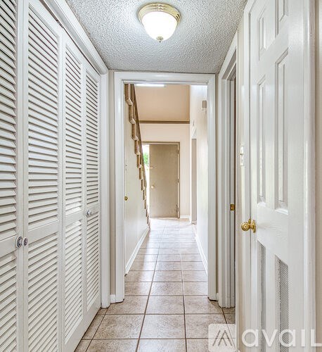 A hallway with white doors and tiled floors.